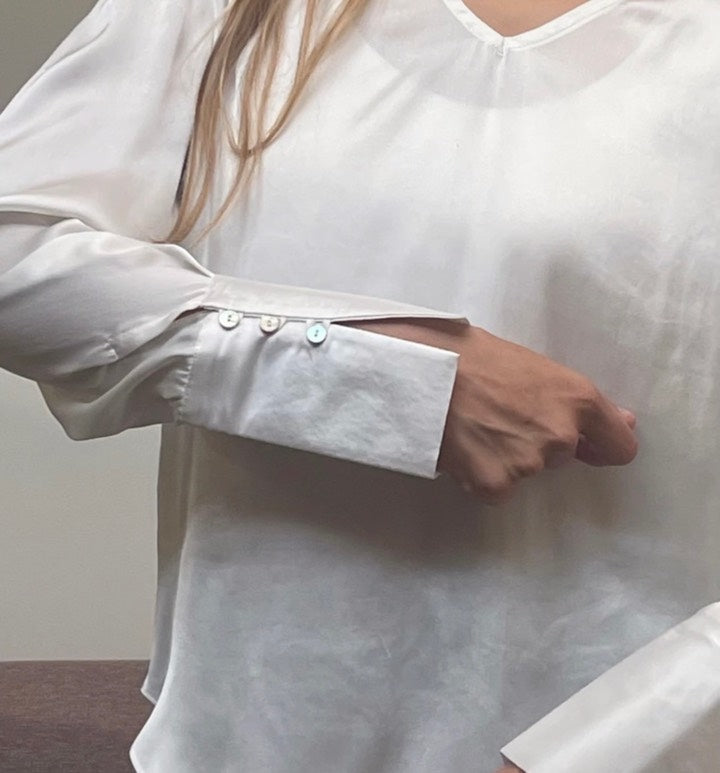 Blusa de seda blanca con puños rígidos con hilera de botones