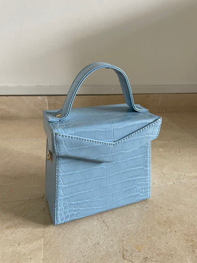 bolso formato cofre azul celeste con asa y con cadena